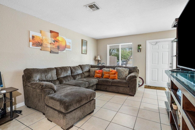 living area with light tile patterned floors, baseboards, visible vents, and a textured ceiling