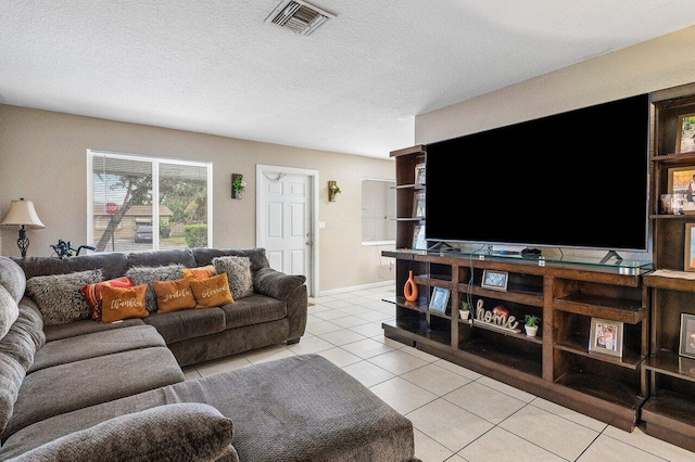 living room featuring light tile patterned floors, visible vents, baseboards, and a textured ceiling