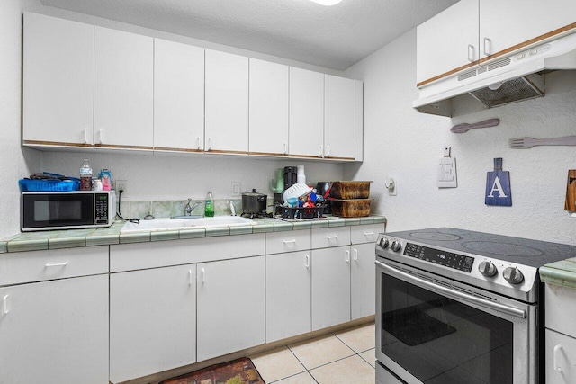 kitchen with tile countertops, stainless steel electric stove, a sink, white cabinets, and under cabinet range hood