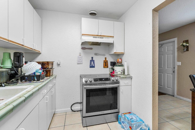 kitchen with light tile patterned flooring, light countertops, electric stove, under cabinet range hood, and white cabinetry