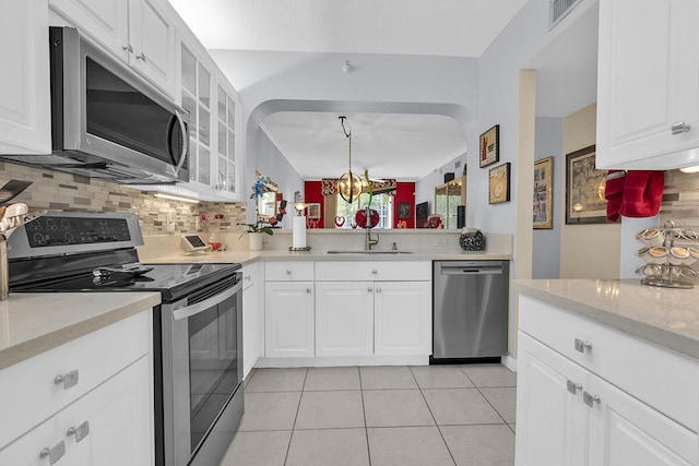 kitchen featuring glass insert cabinets, appliances with stainless steel finishes, decorative backsplash, and a sink