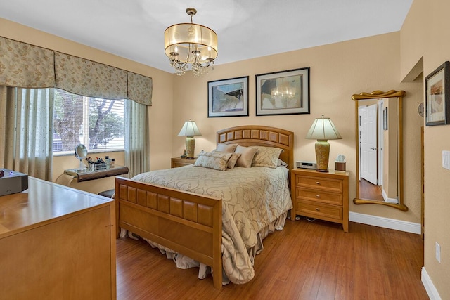 bedroom with a notable chandelier, baseboards, and wood finished floors