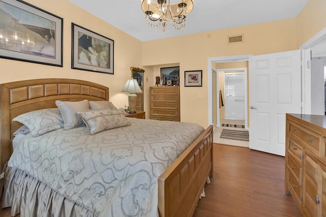 bedroom with dark wood-style floors, visible vents, and an inviting chandelier