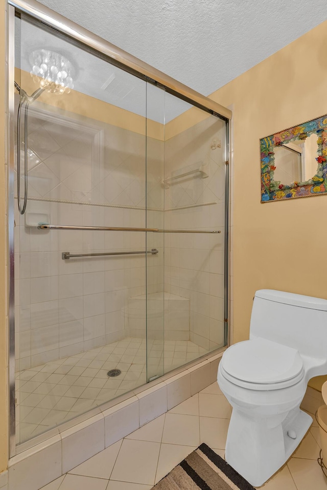 bathroom featuring a textured ceiling, a stall shower, tile patterned flooring, and toilet