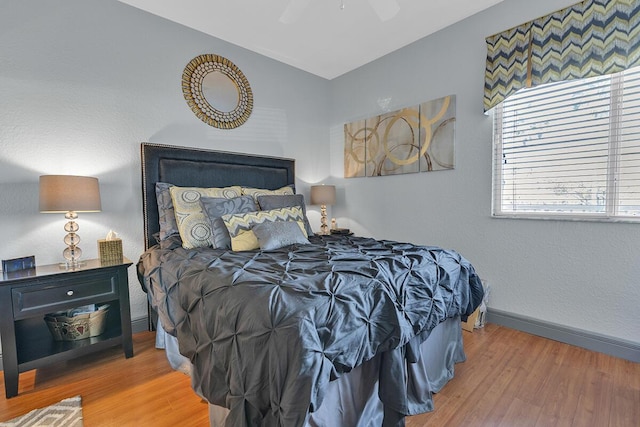 bedroom with vaulted ceiling, wood finished floors, a ceiling fan, and baseboards