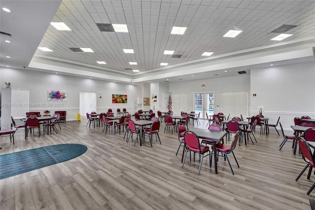 dining room featuring a raised ceiling, light wood-style flooring, and baseboards