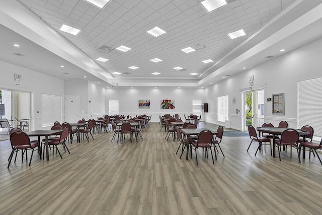 dining space featuring light wood-style flooring, recessed lighting, and a towering ceiling