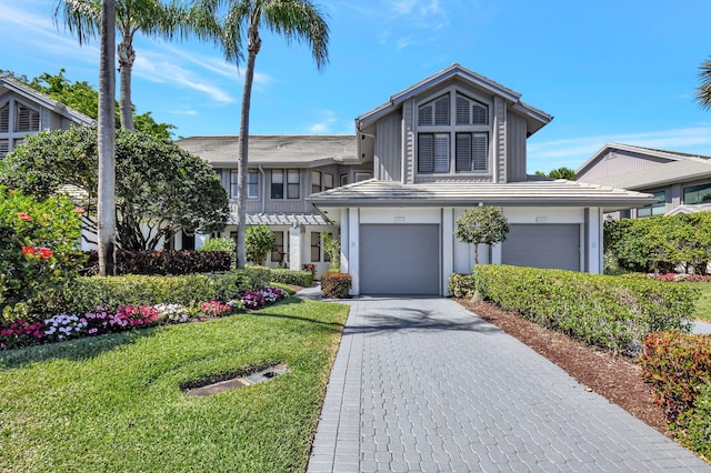 view of front of home featuring a tiled roof, a front lawn, decorative driveway, and an attached garage