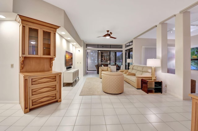 living room with light tile patterned floors, a ceiling fan, and baseboards