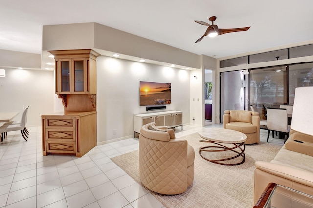 living area featuring baseboards, a ceiling fan, and light tile patterned flooring