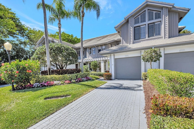 view of front of property with an attached garage, decorative driveway, and a front yard