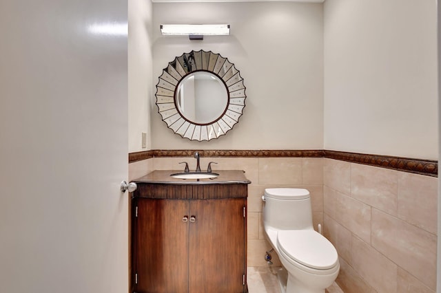 bathroom featuring toilet, wainscoting, tile walls, and vanity