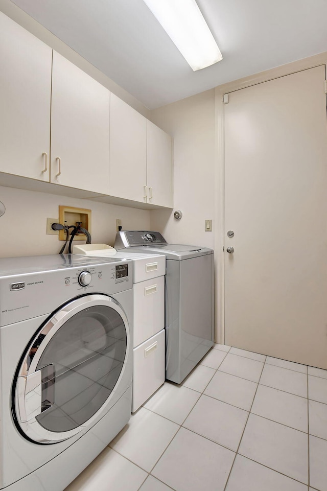 laundry area with cabinet space, light tile patterned flooring, and independent washer and dryer