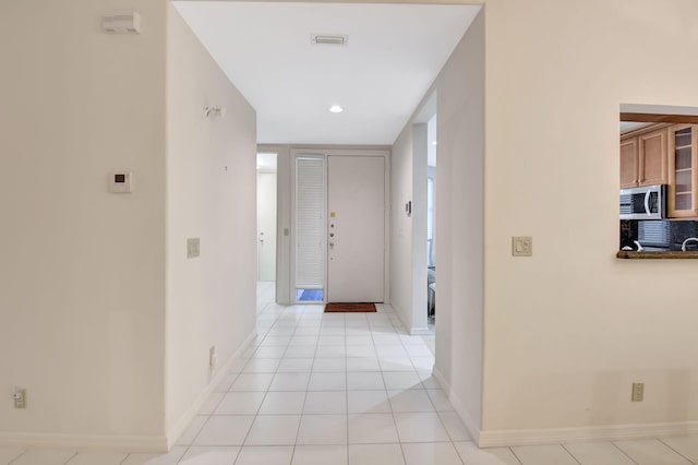 corridor featuring light tile patterned flooring, visible vents, and baseboards