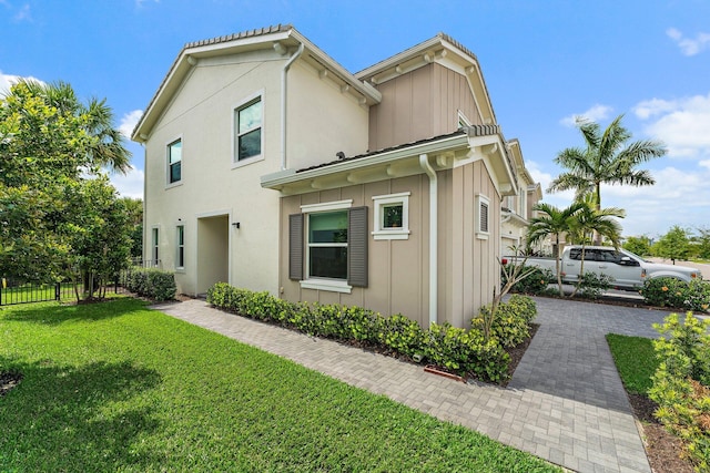 view of property exterior with a yard, board and batten siding, stucco siding, and fence