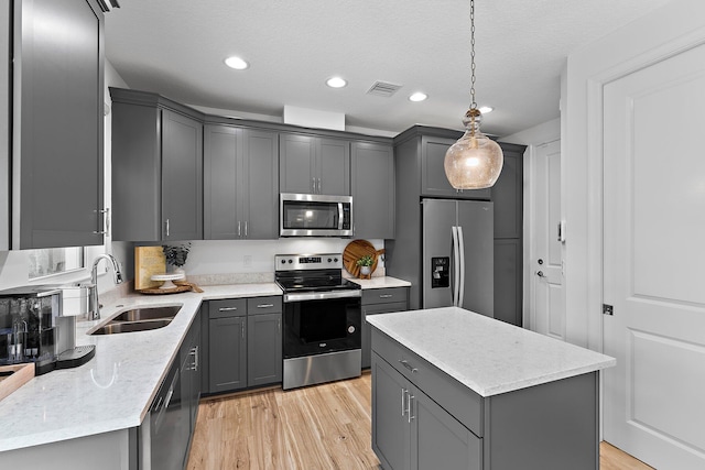 kitchen featuring visible vents, gray cabinetry, light wood-style flooring, a sink, and appliances with stainless steel finishes