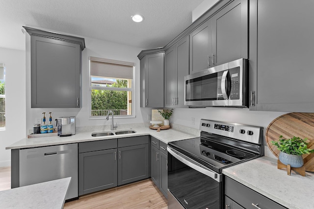 kitchen featuring a sink, stainless steel appliances, light wood-style flooring, and light countertops