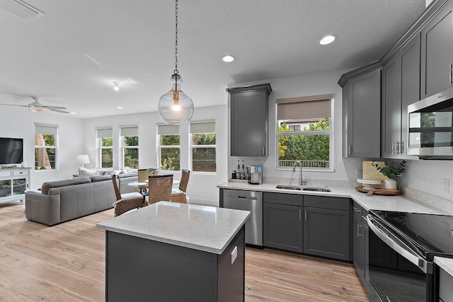 kitchen with a kitchen island, light wood-style flooring, stainless steel appliances, and a sink