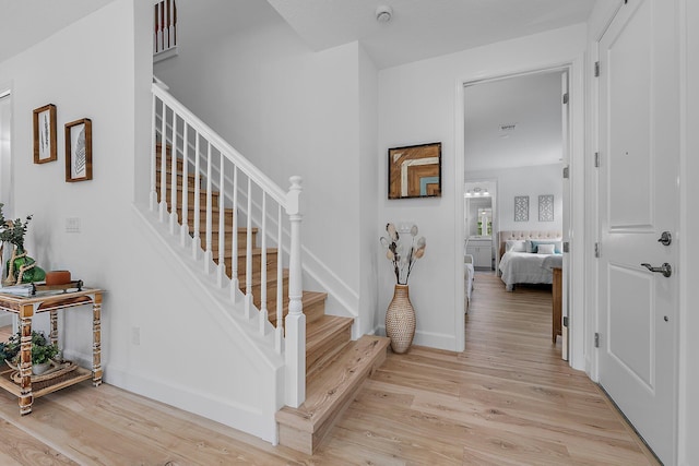 staircase featuring visible vents, wood finished floors, and baseboards