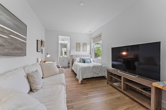 bedroom with ensuite bath and light wood finished floors