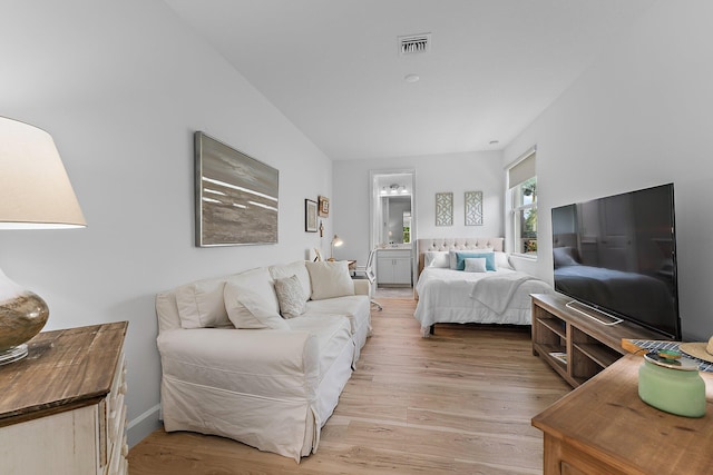 bedroom featuring visible vents, light wood-style floors, and ensuite bath