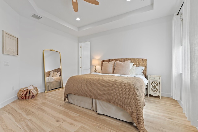 bedroom featuring baseboards, light wood finished floors, a tray ceiling, recessed lighting, and ceiling fan