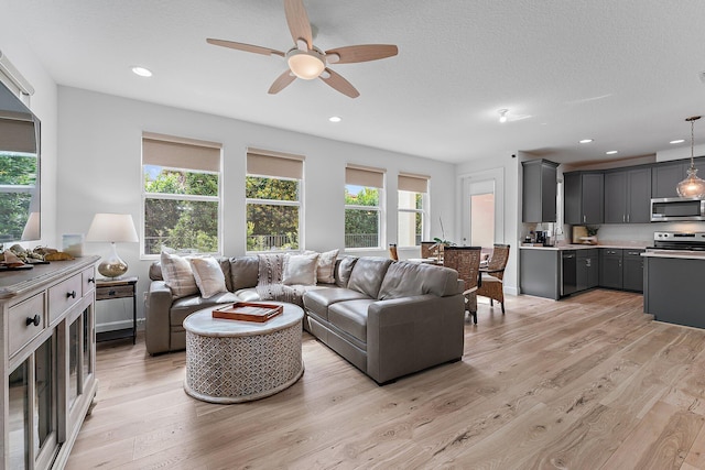 living area with light wood finished floors, recessed lighting, a textured ceiling, and a ceiling fan