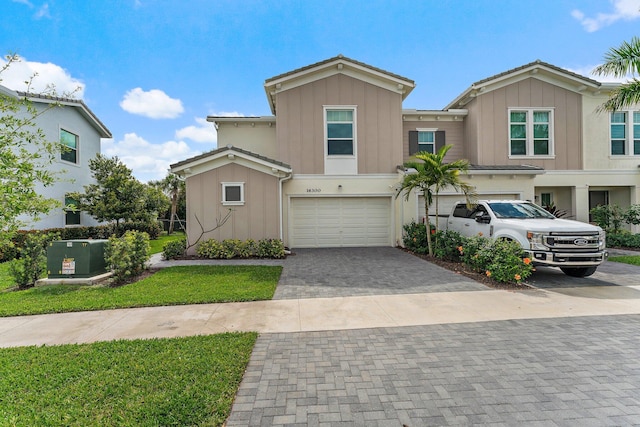 multi unit property with board and batten siding, decorative driveway, and a garage