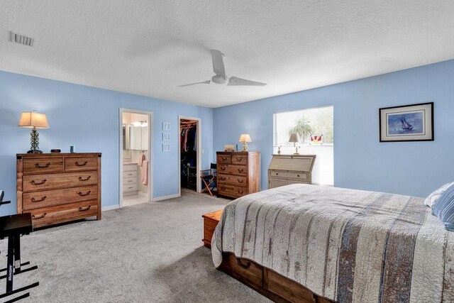 bedroom with carpet, connected bathroom, a closet, visible vents, and a walk in closet