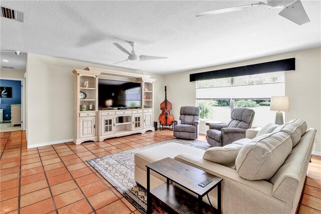 living area with ceiling fan, a textured ceiling, visible vents, light tile patterned flooring, and baseboards
