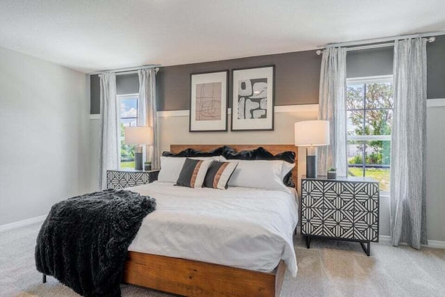 carpeted bedroom featuring multiple windows and baseboards