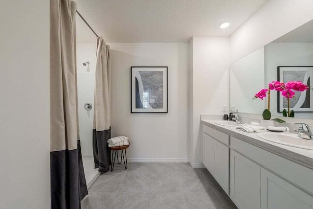 full bath featuring double vanity, a shower with curtain, a sink, and tile patterned floors