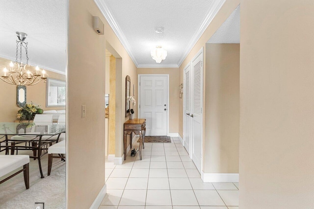 corridor featuring ornamental molding, a textured ceiling, an inviting chandelier, light tile patterned floors, and baseboards