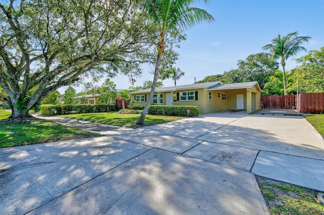 ranch-style home featuring a front yard, fence, driveway, and stucco siding