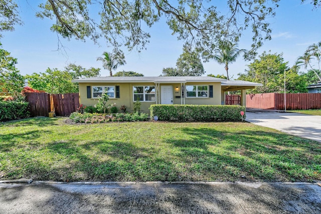 ranch-style home with driveway, an attached carport, fence, a front lawn, and stucco siding