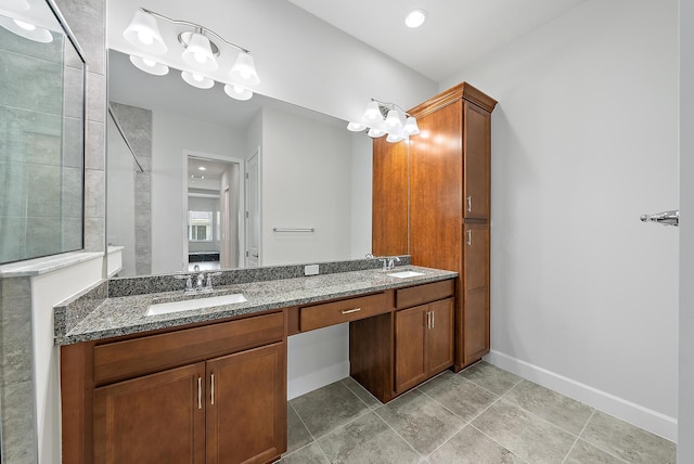 bathroom featuring tiled shower, a sink, baseboards, and double vanity