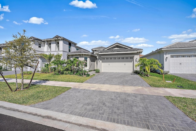 view of front of property featuring a garage, a tile roof, decorative driveway, a front yard, and stucco siding