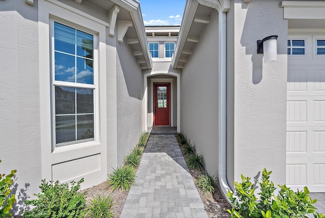 view of exterior entry featuring an attached garage and stucco siding