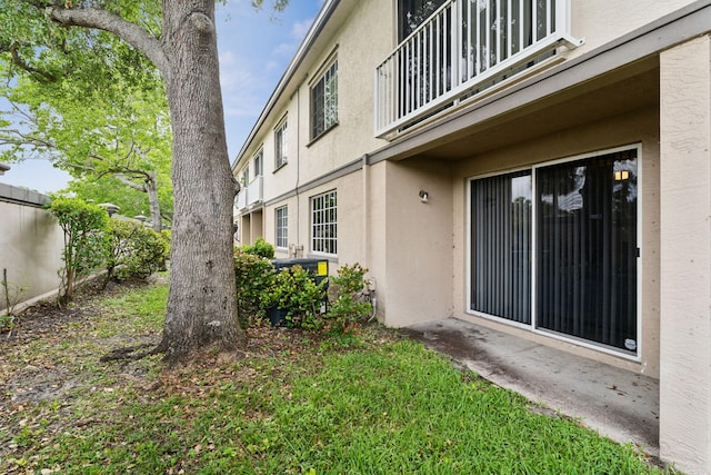 exterior space featuring fence, a balcony, and stucco siding