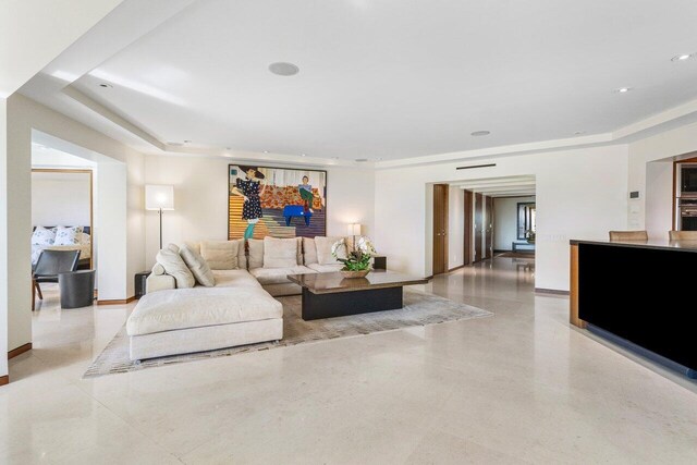 living area featuring recessed lighting, a raised ceiling, and baseboards