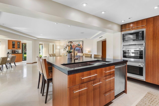 kitchen featuring a breakfast bar, a sink, black microwave, dishwasher, and modern cabinets