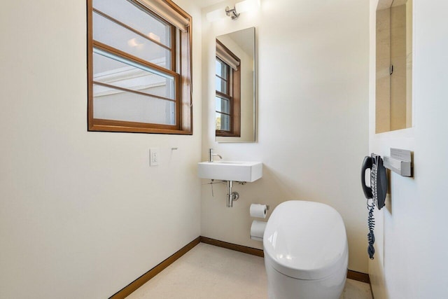 bathroom featuring a sink, baseboards, and toilet