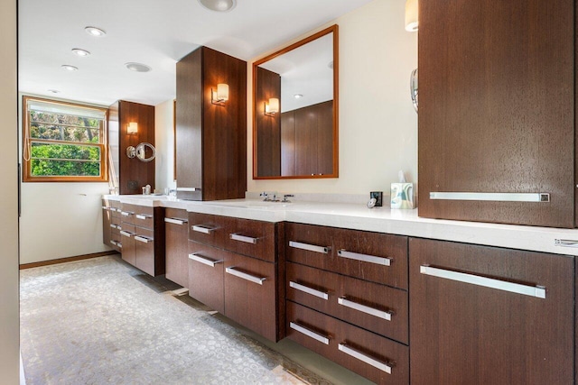 bathroom featuring a sink, recessed lighting, baseboards, and double vanity