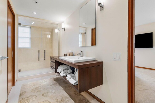 full bathroom featuring vanity, a shower stall, and baseboards