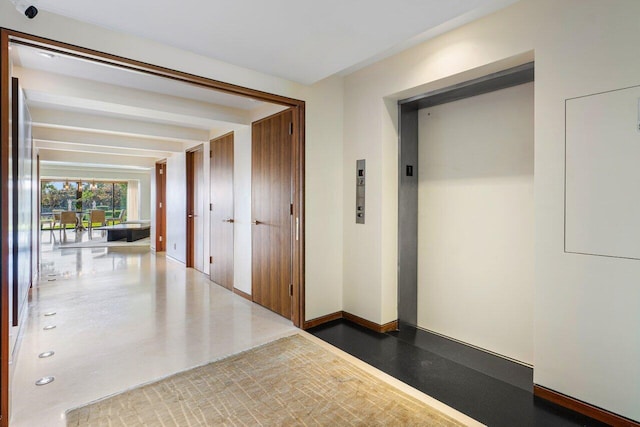 corridor with baseboards and elevator