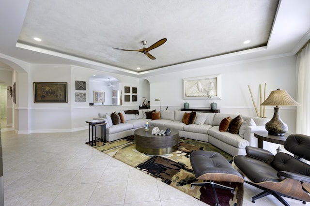 living room featuring arched walkways, a raised ceiling, a ceiling fan, and light tile patterned flooring