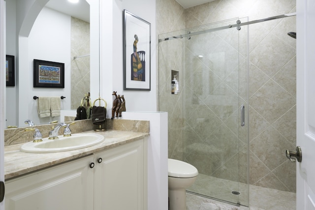 bathroom with a shower stall, toilet, and vanity