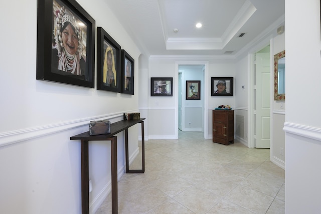 hall with a tray ceiling, recessed lighting, visible vents, and ornamental molding