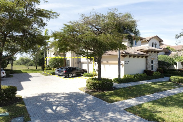 view of front of property with a tile roof, a front yard, stone siding, and stucco siding