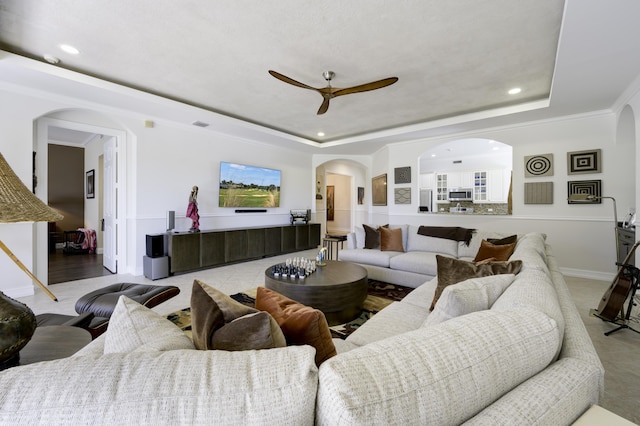 living room with a raised ceiling, recessed lighting, and arched walkways